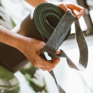 Close-up of a woman's hands holding a yoga mat with a strap. Perfect for fitness and lifestyle concepts.